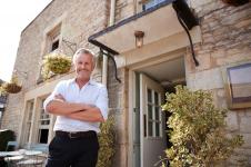 senior male restaurant pub owner stands outside th VAXFPD4